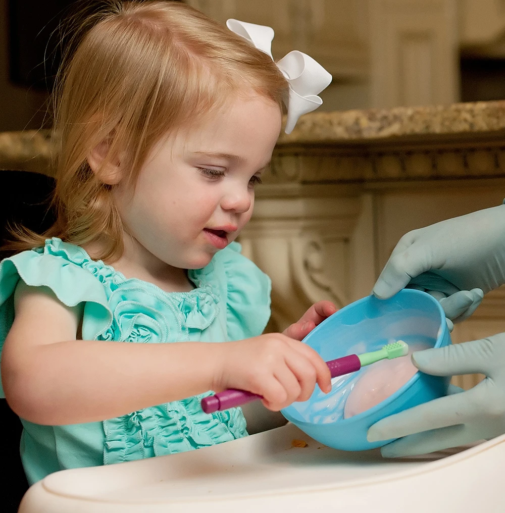 Toddler receives support for independent feeding with the mini tip Z vibe
